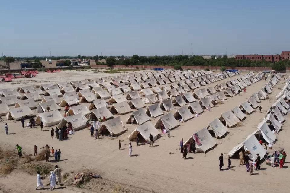 A humanitarian facility, with rows of tents, is set up in a dusty field in Pakistan.
